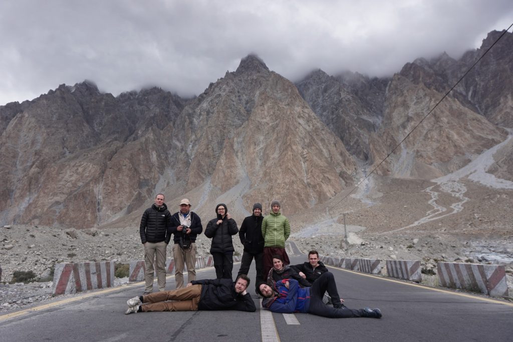 Group of tourists on road in northern Pakistan with mountains in background