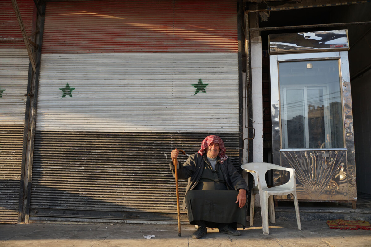 Local Syrian in front of his shop with the Syrian flag