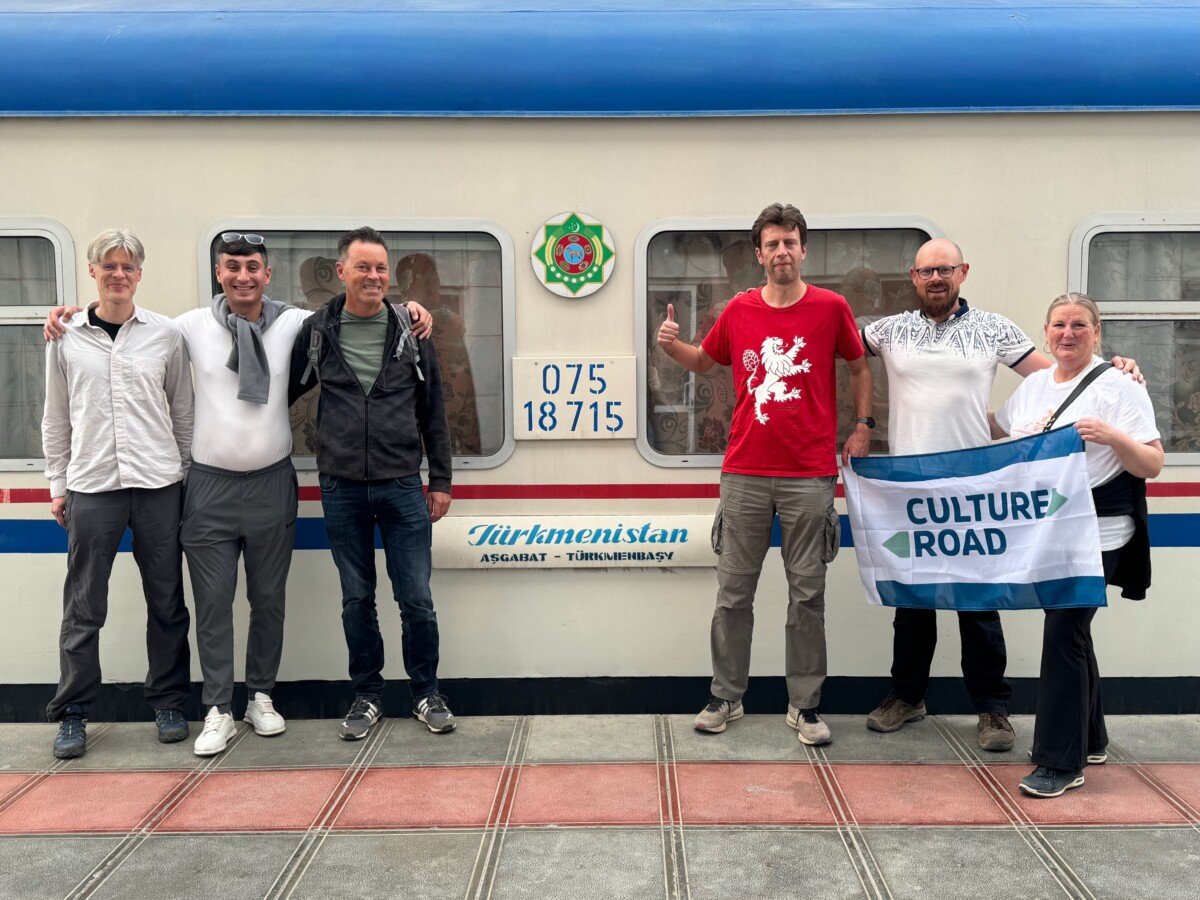 Group of tourists in front of Turkmenistan train with a CultureRoad flag